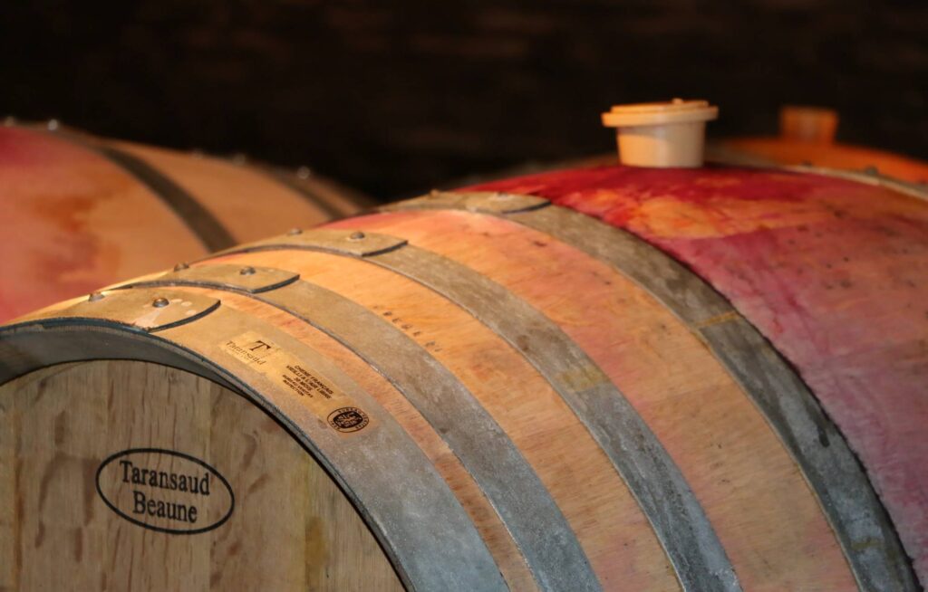A close-up image of Domaine A.-F.Gros Burgundy Wine barrel. It has a classic color of light barrel brown with stripe of red, the front is stamped with the text, "Taransaud Beaune"