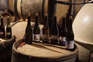 6 bottles of domaine didon wines on top of the wooden barrel in their cellar.